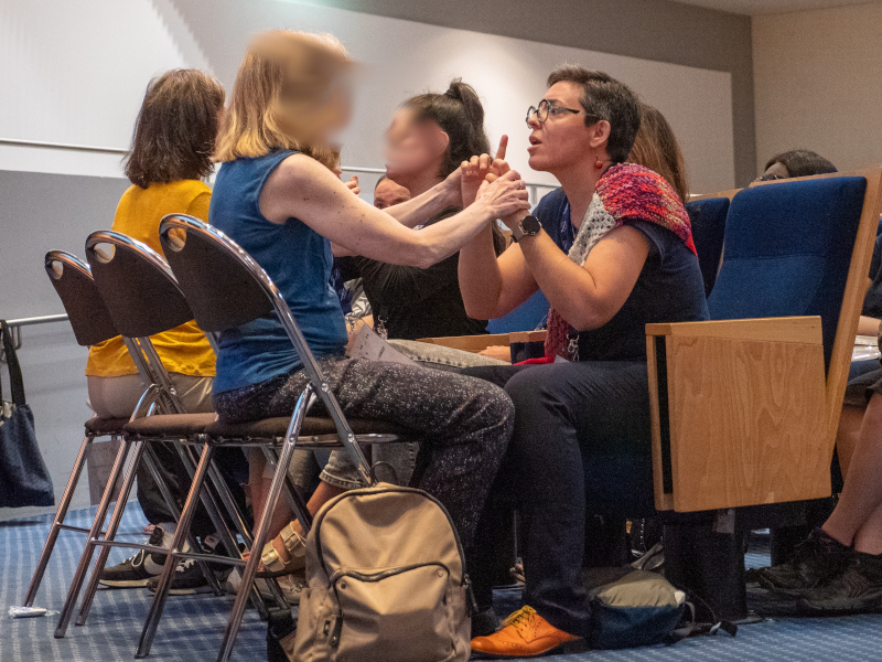 Elodie Thiercelin consultante Elodie Thiercelin est assise face à une personne sourdaveugle dans une salle de conférence et traduit en LSF tactile une intervention lors de la Journée Mondiale de la Surdicécité
